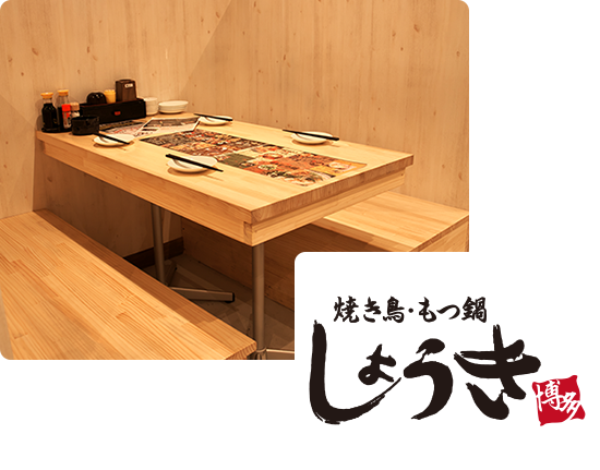 画像:木目調の店内でテーブルも木のテーブル。テーブルには、4人分のお箸をお皿が用意されており、中央にはメニュー。テーブルの端にはソースや小皿が用意されています。