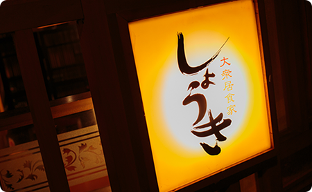 画像:お店の外、ライトで明るく光る、大衆居食家しょうきの看板。